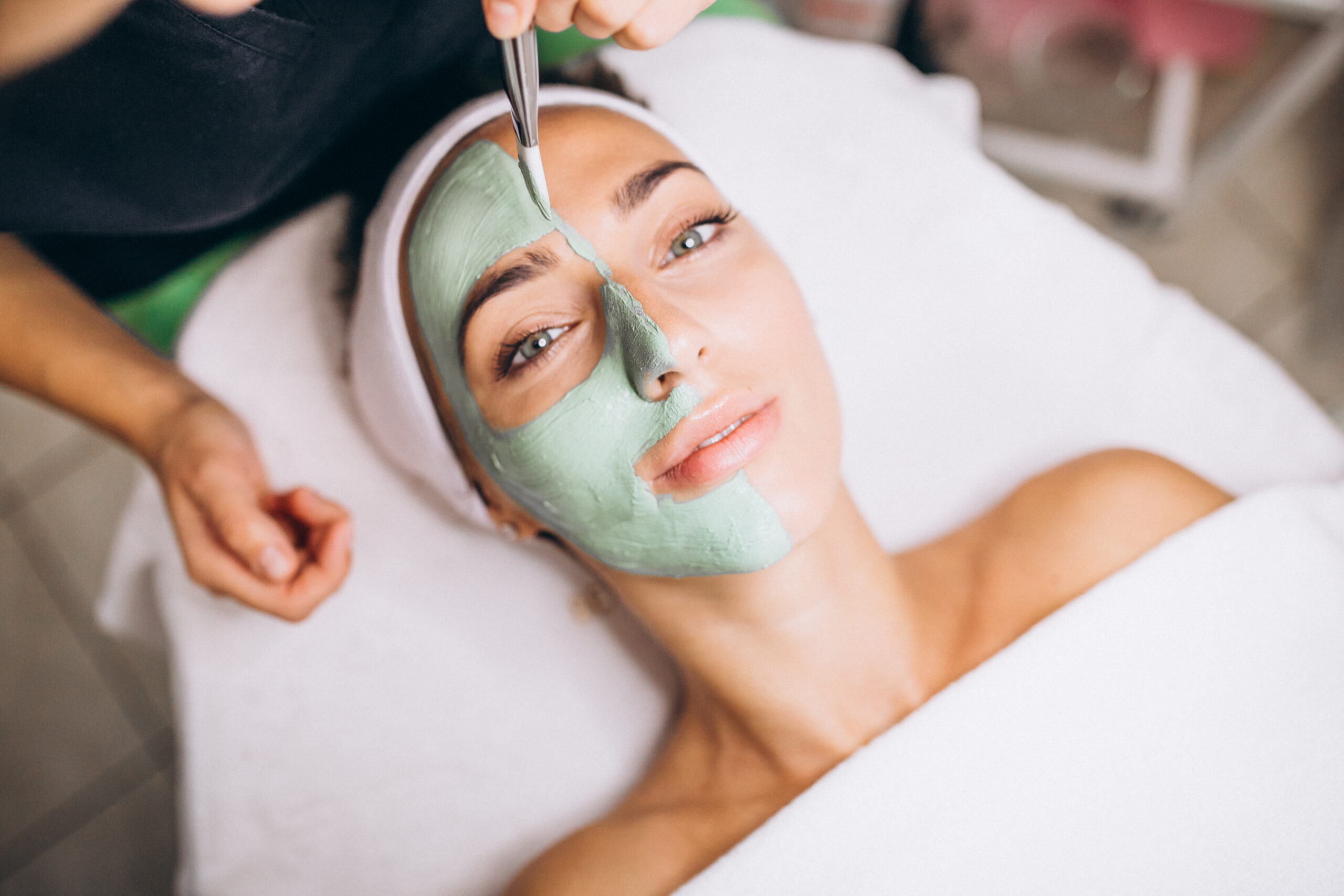 Cosmetologist applying mask on a face of client in a beauty salon